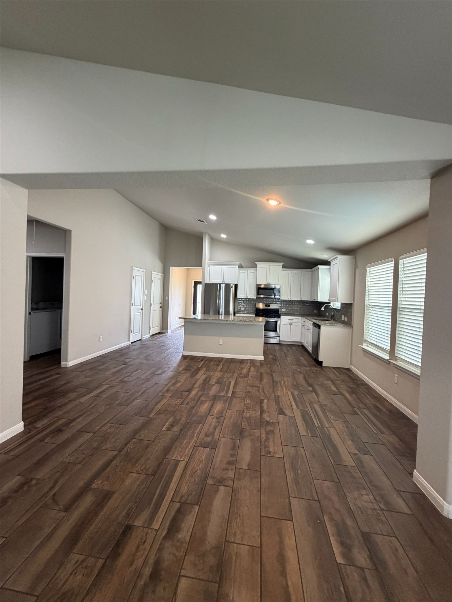 248 Falling Star Lane Georgetown, TX 78628 - Photo 6 of 16 An open-concept living space integrates a well-appointed kitchen with warm wood-look flooring and soaring vaulted ceilings.