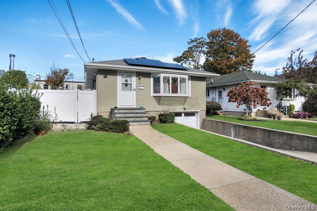 Bungalow featuring an attached garage and roof mounted solar panels