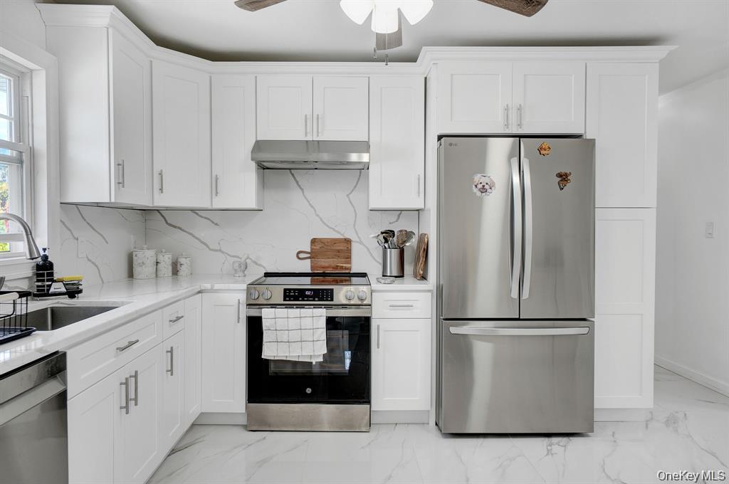 61 South Merrick Road Massapequa, NY 11758 - Photo 12 of 29 Kitchen with stainless steel appliances, a ceiling fan, light marble finish floors, and backsplash