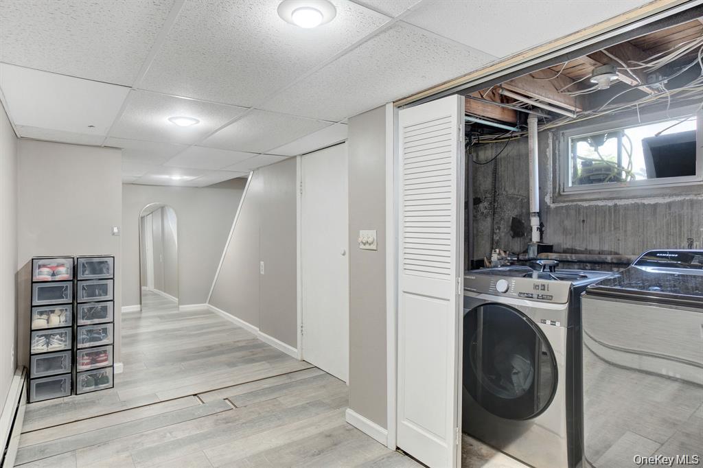 61 South Merrick Road Massapequa, NY 11758 - Photo 21 of 29 Laundry area with a paneled ceiling, light wood-style flooring, washer and dryer, and a baseboard radiator