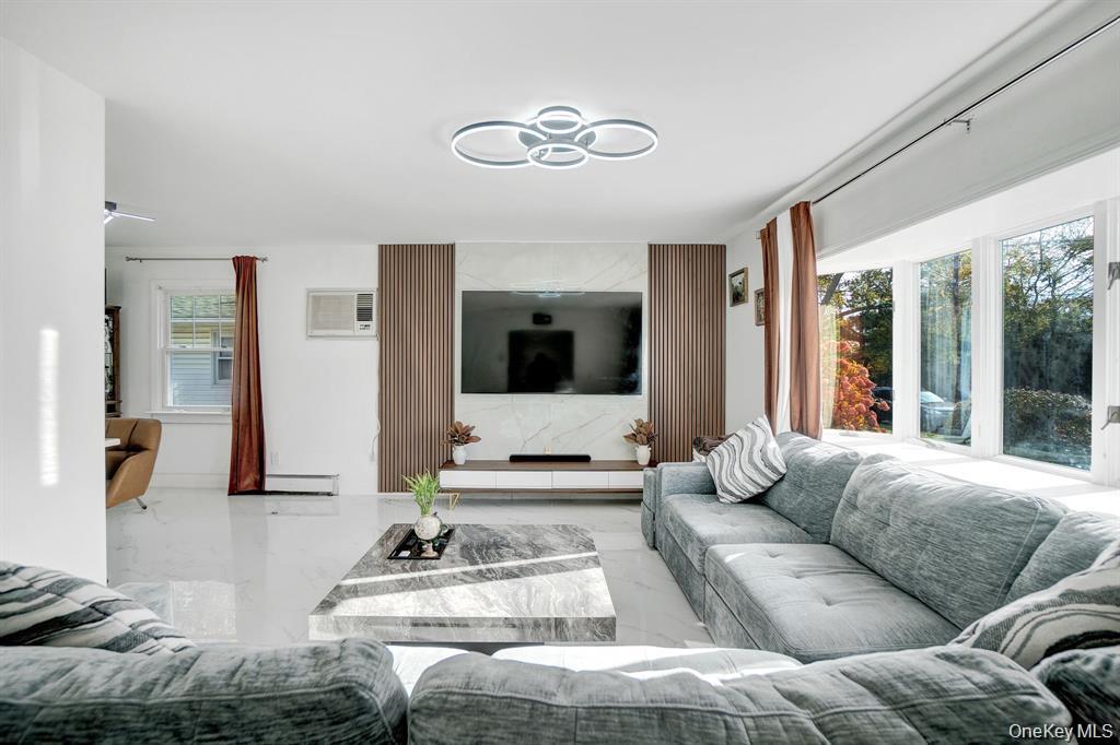 61 South Merrick Road Massapequa, NY 11758 - Photo 6 of 29 Living room with plenty of natural light, marble tiled floors, a baseboard radiator, and an AC wall unit