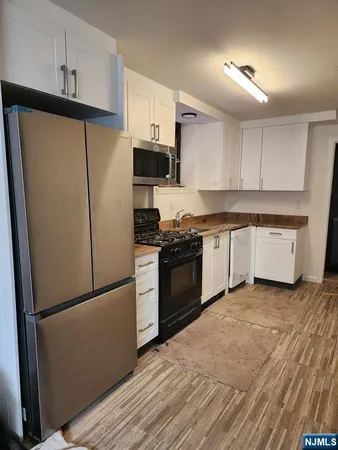 a kitchen with a refrigerator a stove top oven and white cabinets