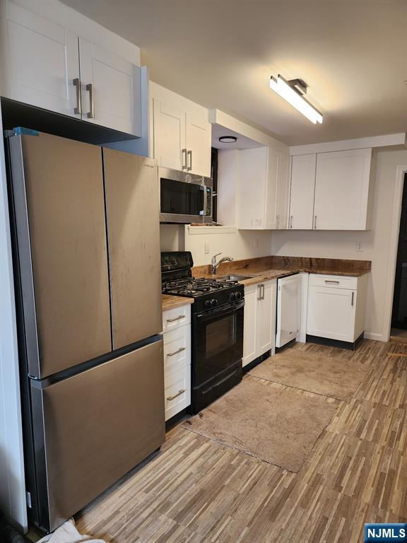 403 Anderson Avenue, Unit 7A Fairview, NJ 07022 - Photo 2 of 3 a kitchen with a refrigerator a stove top oven and white cabinets