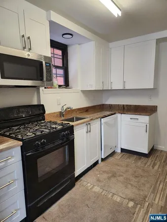 a kitchen with granite countertop a stove top oven microwave and cabinets