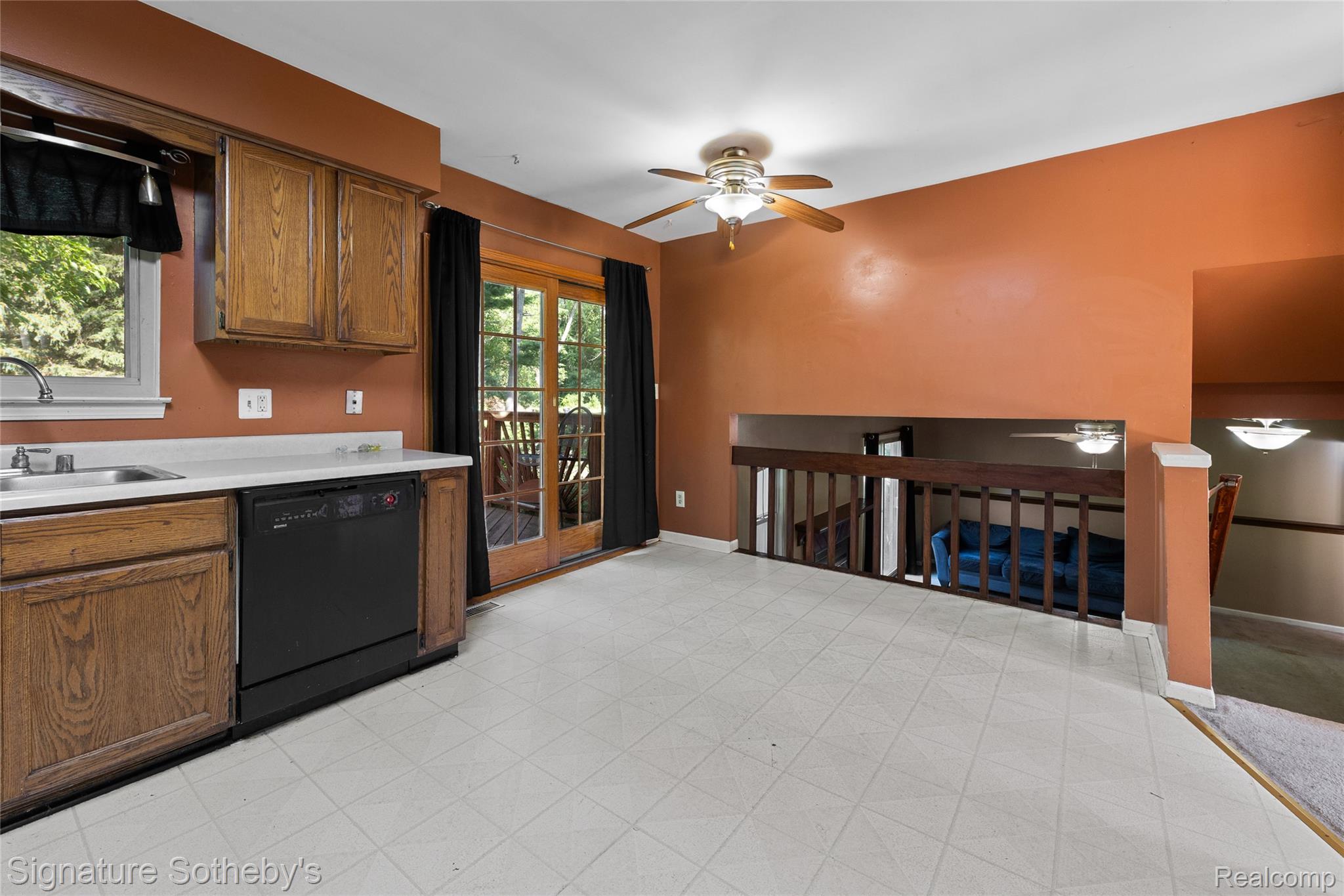 Kitchen area featuring wood cabinetry, a white countertop, and a black dishwasher