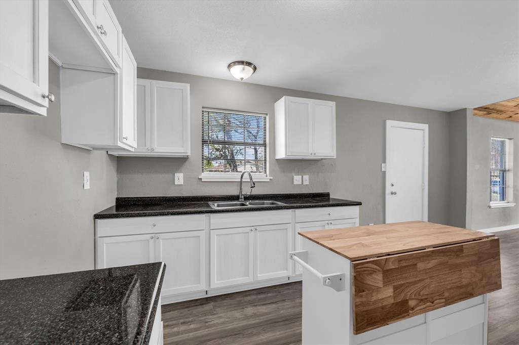 308 South Herman Street Mexia, TX 76667 - Photo 11 of 28 a kitchen with granite countertop a sink stove and cabinets