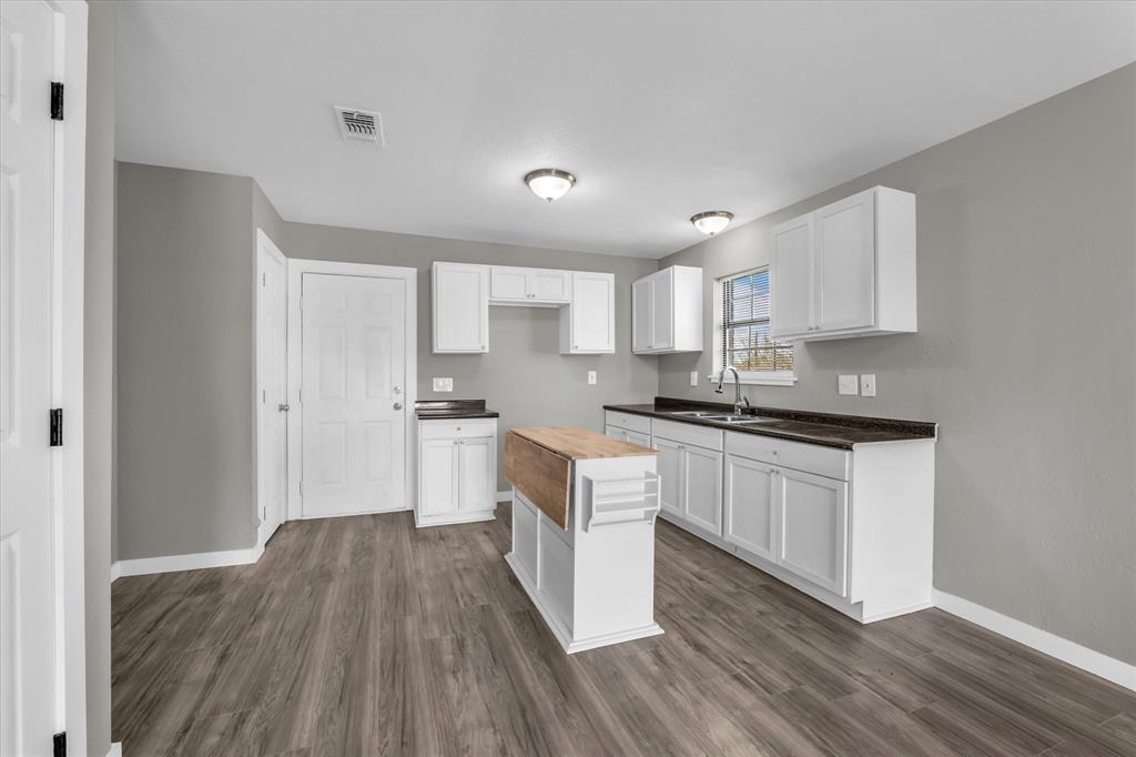 308 South Herman Street Mexia, TX 76667 - Photo 9 of 28 a kitchen with granite countertop a stove top oven and cabinets