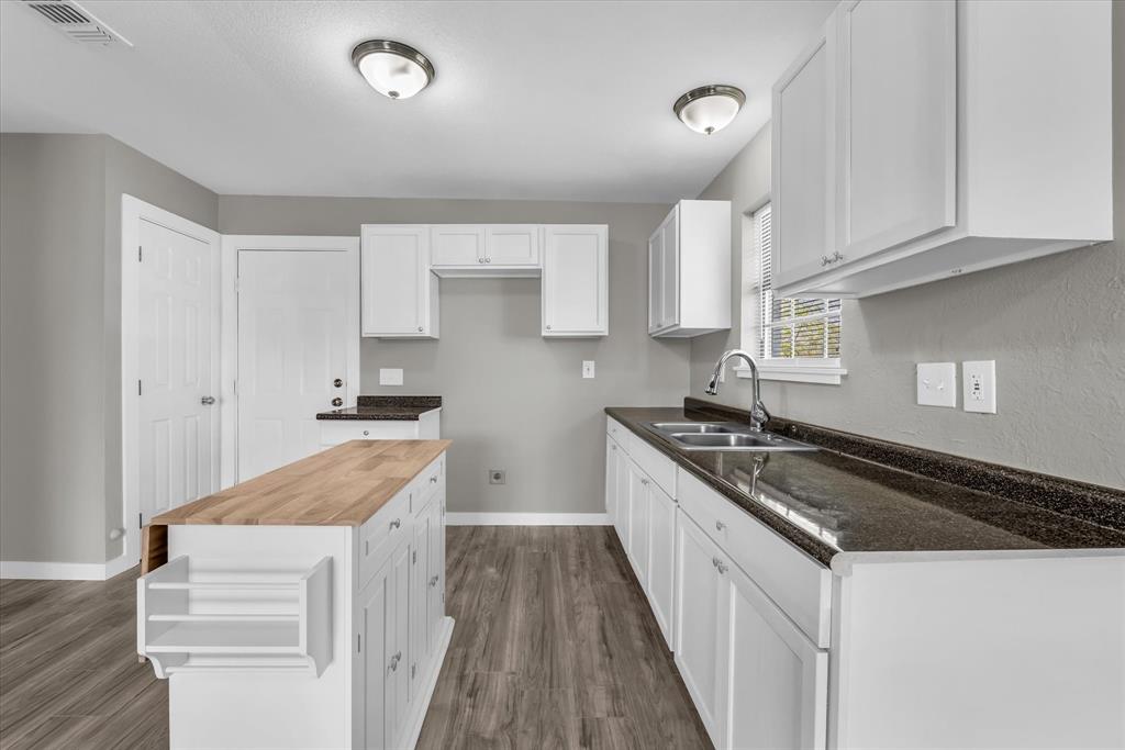 308 South Herman Street Mexia, TX 76667 - Photo 10 of 28 a kitchen with granite countertop a sink stove and cabinets