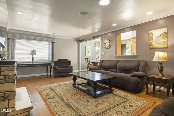 a kitchen with stainless steel appliances granite countertop a refrigerator a stove top oven a sink dishwasher a dining table and chairs with wooden floor