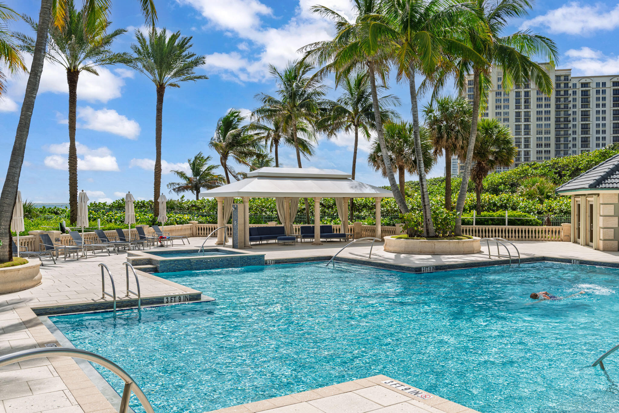 3920 North Ocean Drive, Unit 7A Singer Island, FL 33404 - Photo 23 of 35 a view of a swimming pool with a table and chairs under palm trees