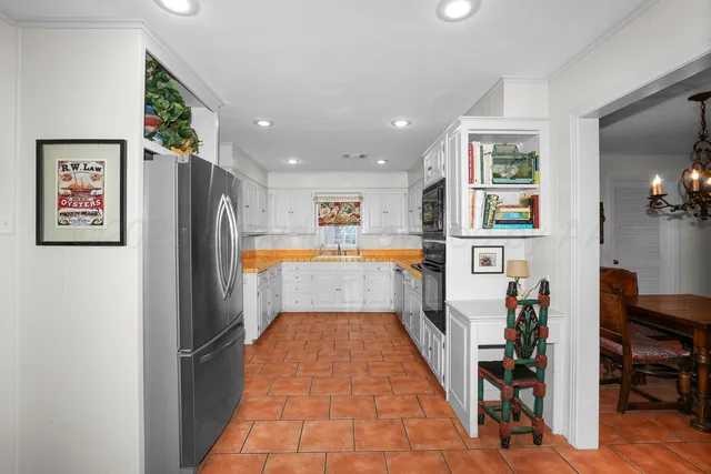 a hallway with a large refrigerator and a bookshelf