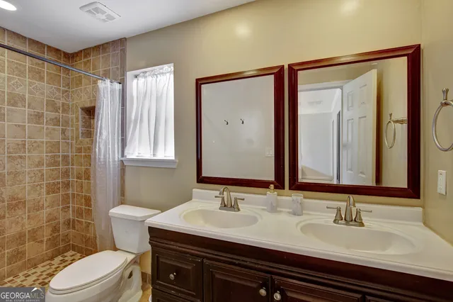 a bathroom with a double vanity sink toilet and mirror