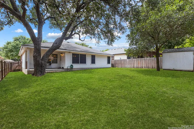 a view of a house with a yard deck and a large tree