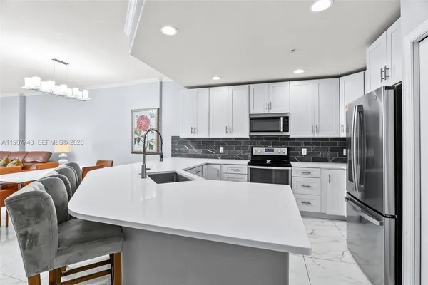 a kitchen with kitchen island a white counter top space stainless steel appliances and cabinets