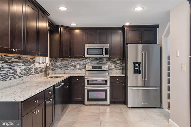 a kitchen with stainless steel appliances granite countertop a refrigerator and a stove