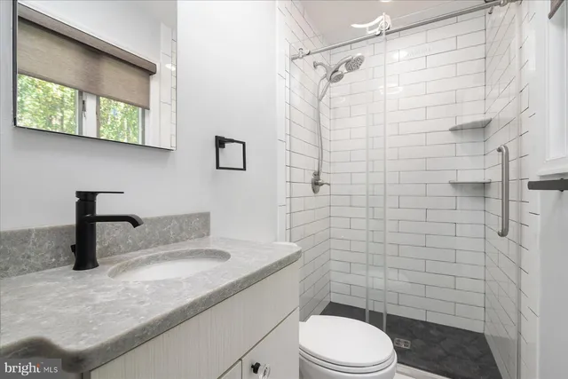 a bathroom with a granite countertop sink toilet a mirror and shower
