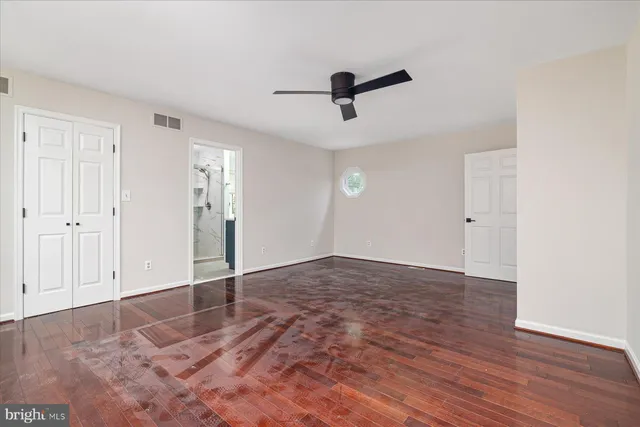 an empty room with wooden floor and windows