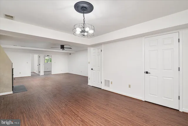a view of empty room with wooden floor and chandelier