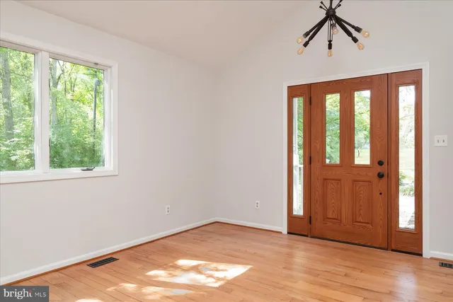 a view of an empty room with wooden floor and windows