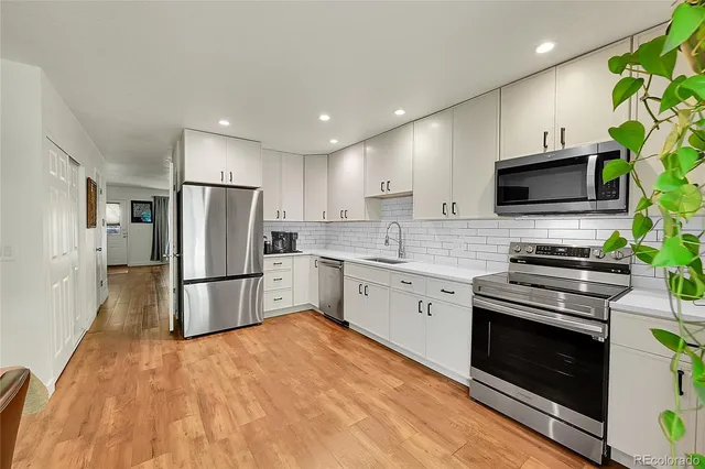 a kitchen with a sink a microwave a refrigerator and cabinets