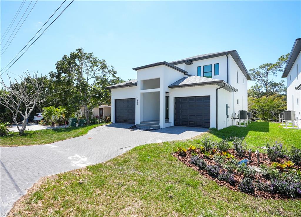 Contemporary home featuring stucco siding, a front yard, decorative driveway, and a garage