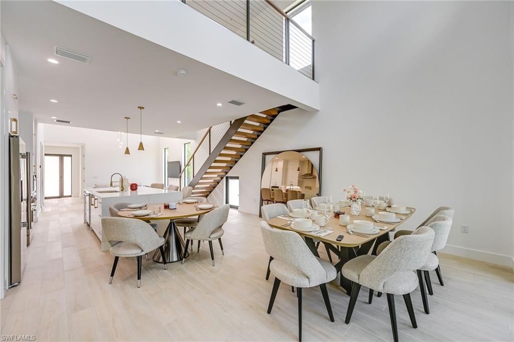 3400 Canal Street Naples, FL 34112 - Photo 10 of 28 Dining room featuring stairway, light wood-type flooring, recessed lighting, and a towering ceiling