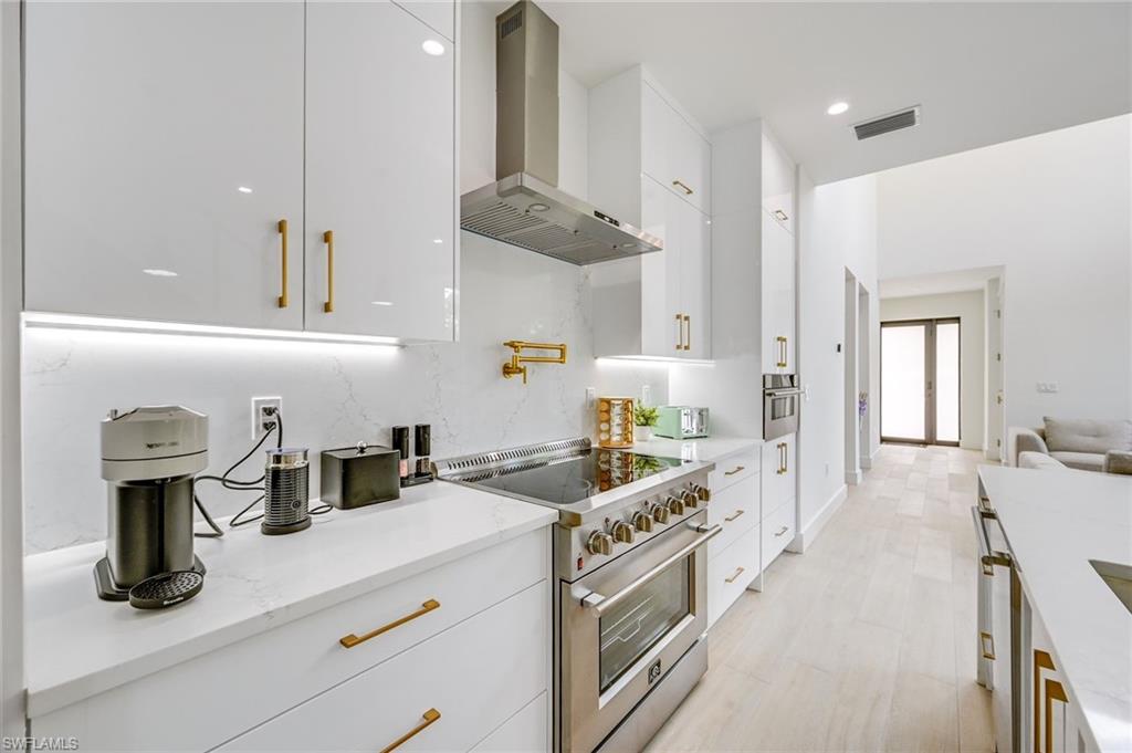 3400 Canal Street Naples, FL 34112 - Photo 11 of 28 Kitchen with high end stainless steel range oven, wall chimney range hood, white cabinets, and recessed lighting