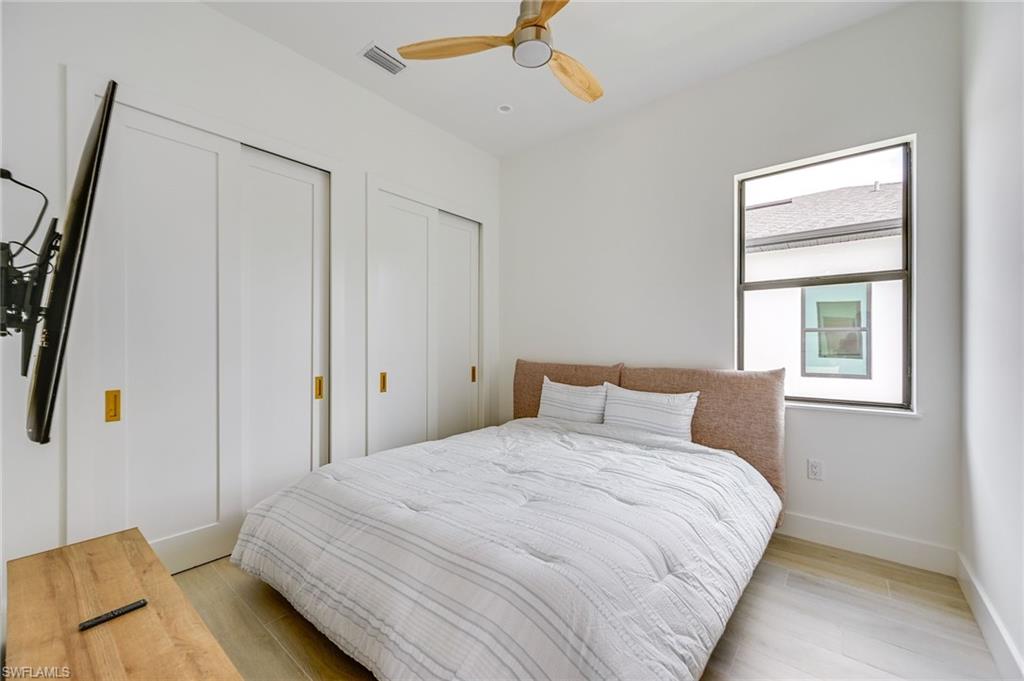 3400 Canal Street Naples, FL 34112 - Photo 24 of 28 Bedroom featuring multiple closets, light wood-style flooring, and ceiling fan