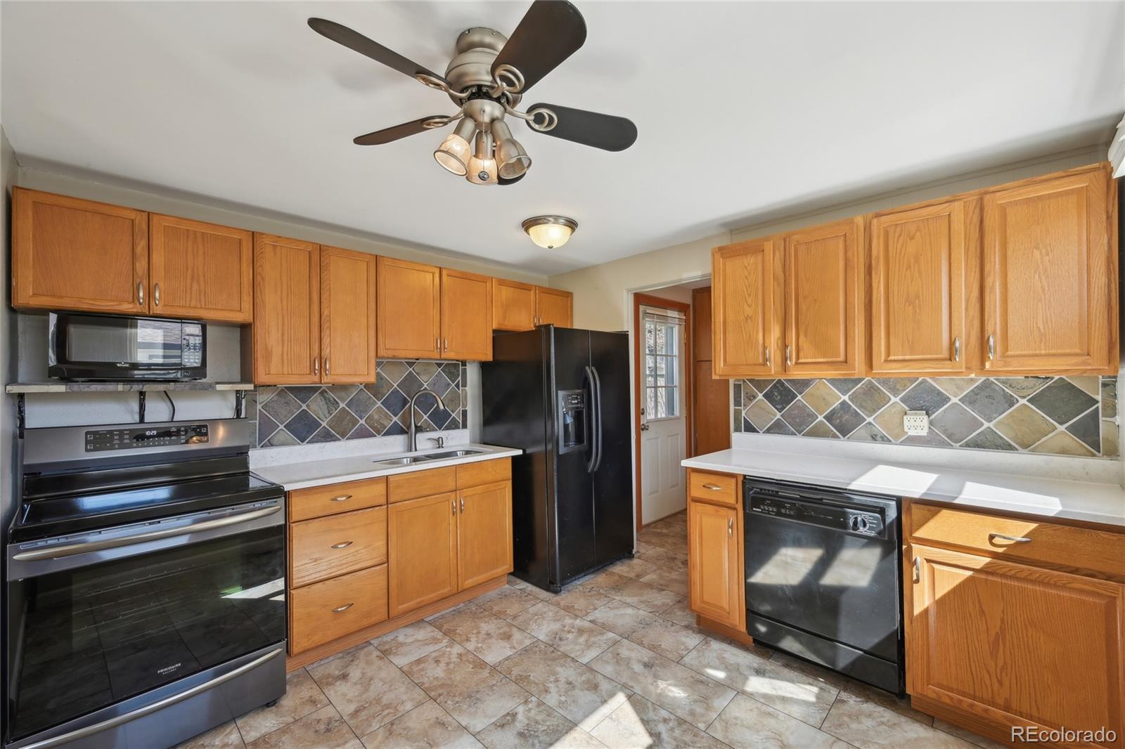 6819 Reno Drive Arvada, CO 80002 - Photo 13 of 32 a kitchen with stainless steel appliances granite countertop a stove and a refrigerator
