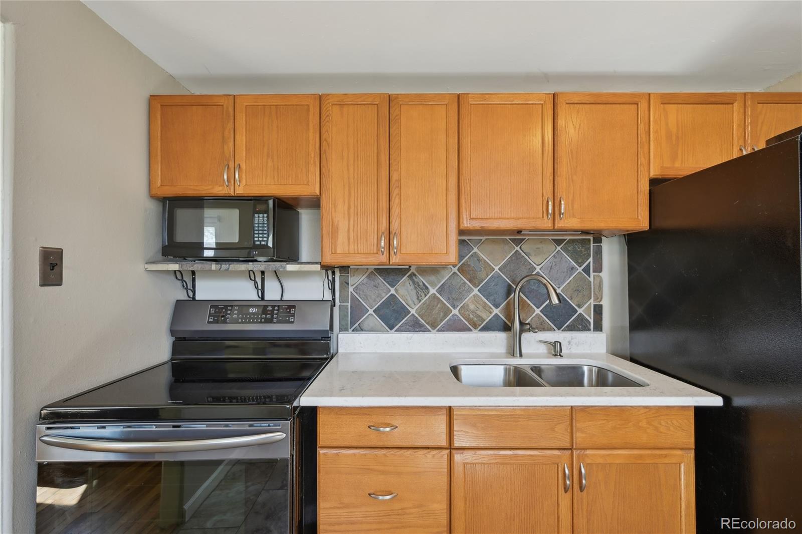 6819 Reno Drive Arvada, CO 80002 - Photo 14 of 32 a kitchen with wooden cabinets and a stove top oven
