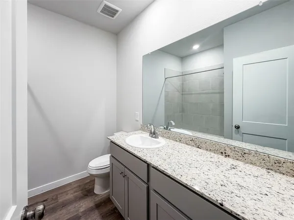 a bathroom with a granite countertop sink a toilet and a mirror