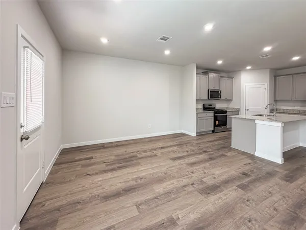 a view of kitchen with kitchen island a sink wooden floor and a stove top oven