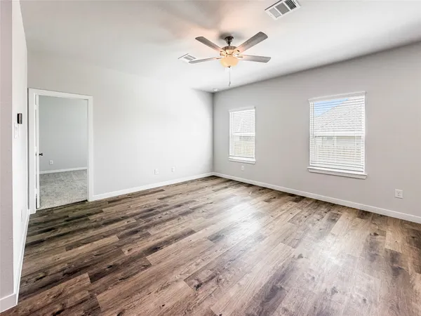 an empty room with wooden floor and windows