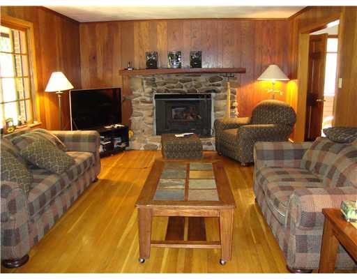 Living Room. Stone Fireplace with Buck Stove Woodburner Insert.  Hardwood Floors.