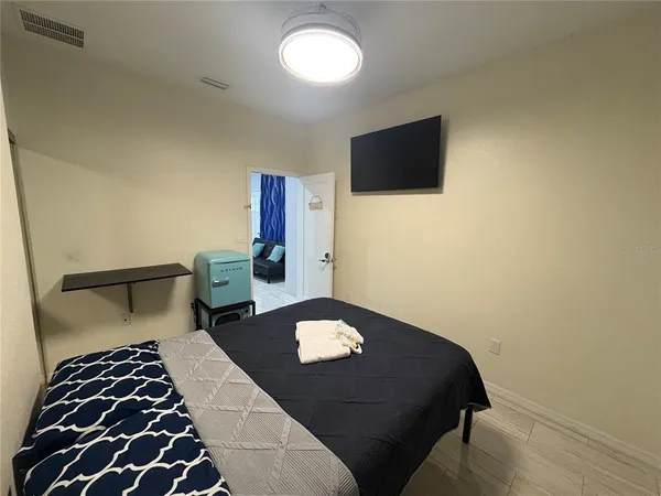 a bedroom with a bed and a flat tv screen on the dresser