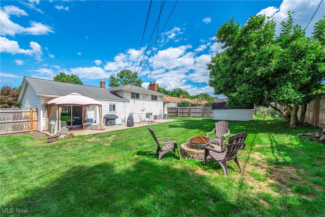 13765 Newton Road Cleveland, OH 44130 - Photo 41 of 42 Back of property with a patio, a gazebo, a fenced backyard, an outdoor fire pit, and a shed