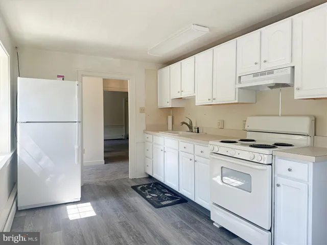 a kitchen with cabinets appliances wooden floor and a window