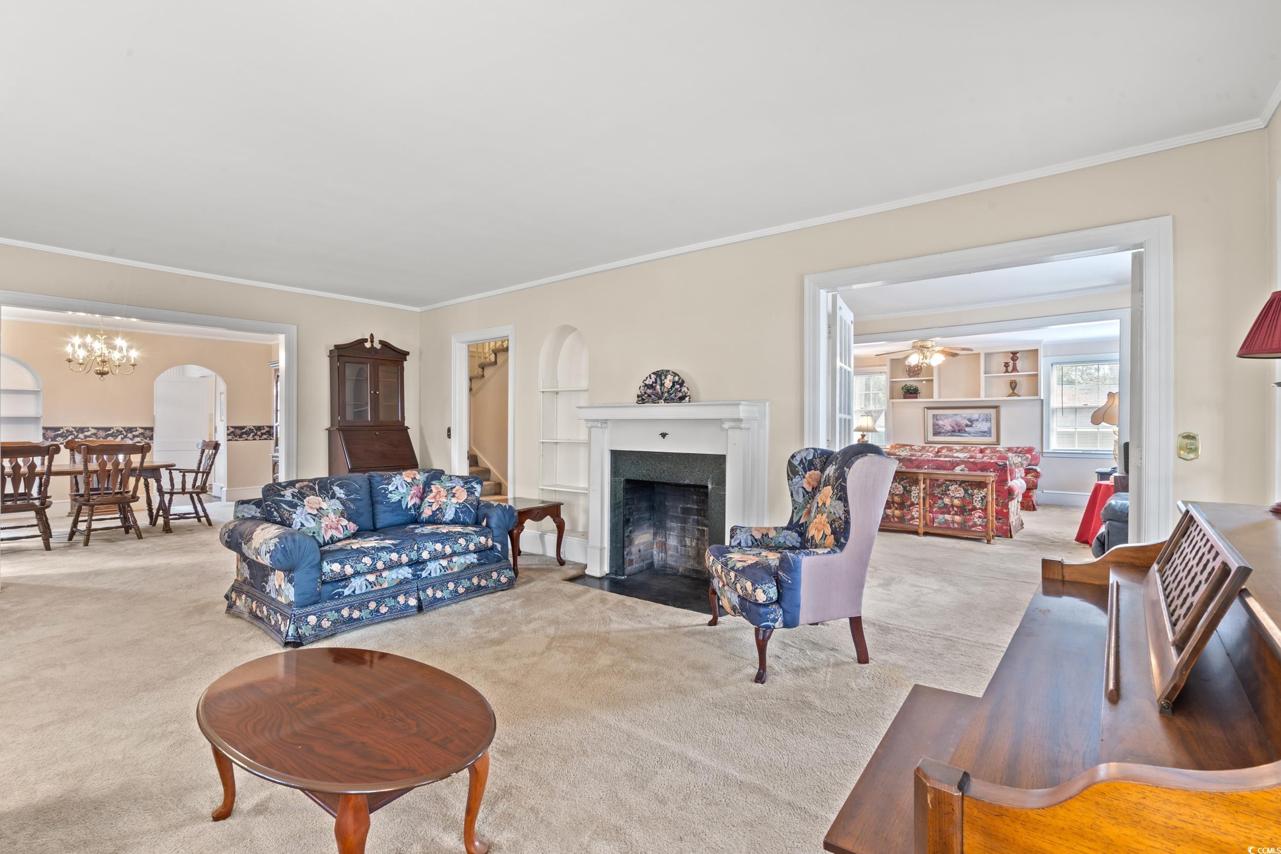 310 North Main Street Mullins, SC 29574 - Photo 27 of 35 Living room with ornamental molding, carpet flooring, a fireplace with flush hearth, and a chandelier