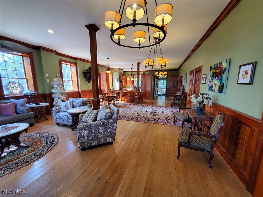 150 Main Street Hayesville, OH 44805 - Photo 6 of 50 Living room with wainscoting, crown molding, wood finished floors, a chandelier, and wooden walls.