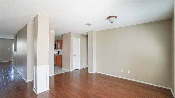 a view of an empty room with wooden floor and a window