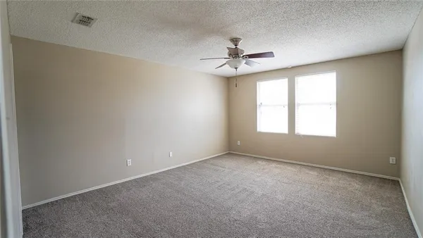 an empty room with a window and a ceiling fan