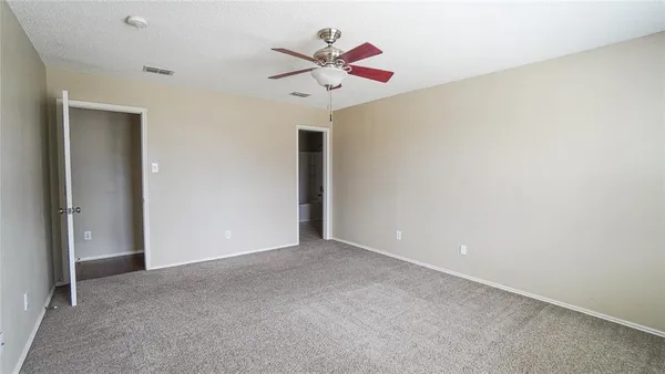 an empty room with ceiling fan and window