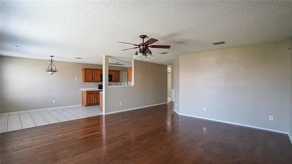 an empty room with wooden floor and a ceiling fan