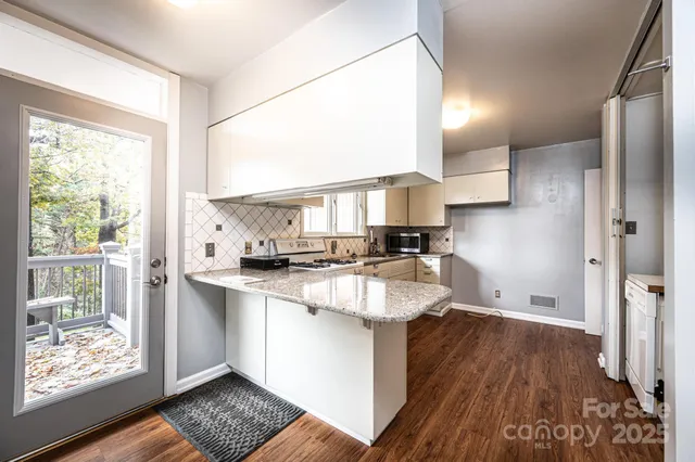 a kitchen with stainless steel appliances granite countertop a refrigerator a sink dishwasher a stove and white countertops with wooden floor