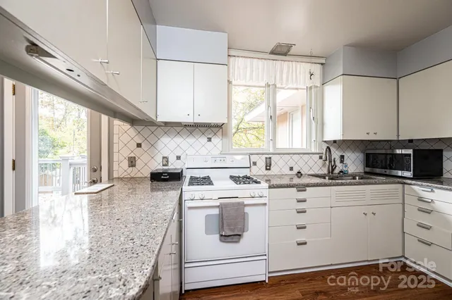a kitchen with granite countertop a sink a window stainless steel appliances and cabinets