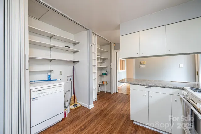 a room with a wooden floor and white cabinets