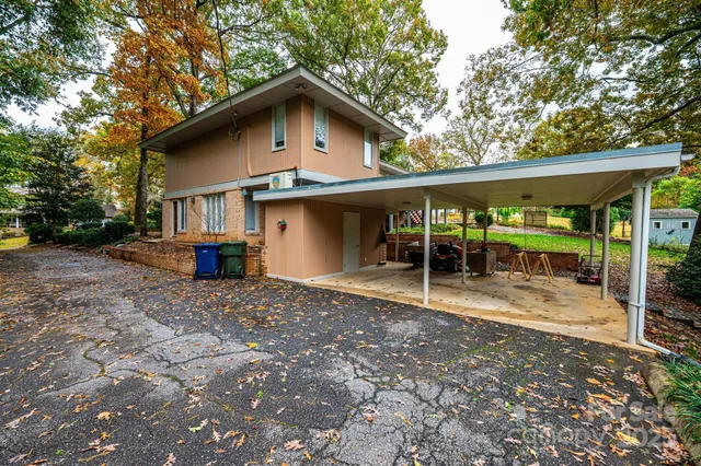 a view of a house with porch and chairs next to a yard