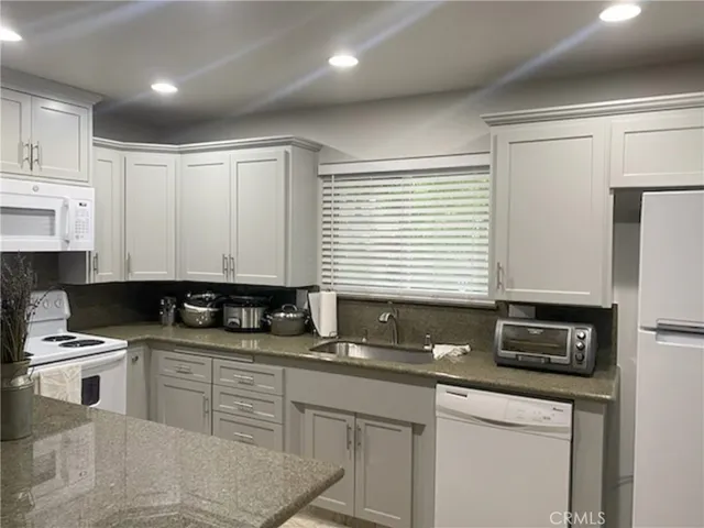 a kitchen with stainless steel appliances granite countertop a sink a stove a microwave a counter space and cabinets