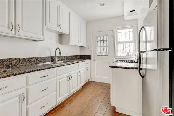 a kitchen with white cabinets and wooden floor