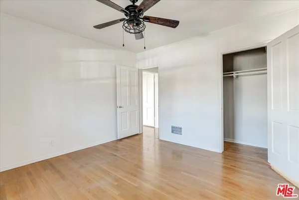 a view of an empty room with a window and wooden floor